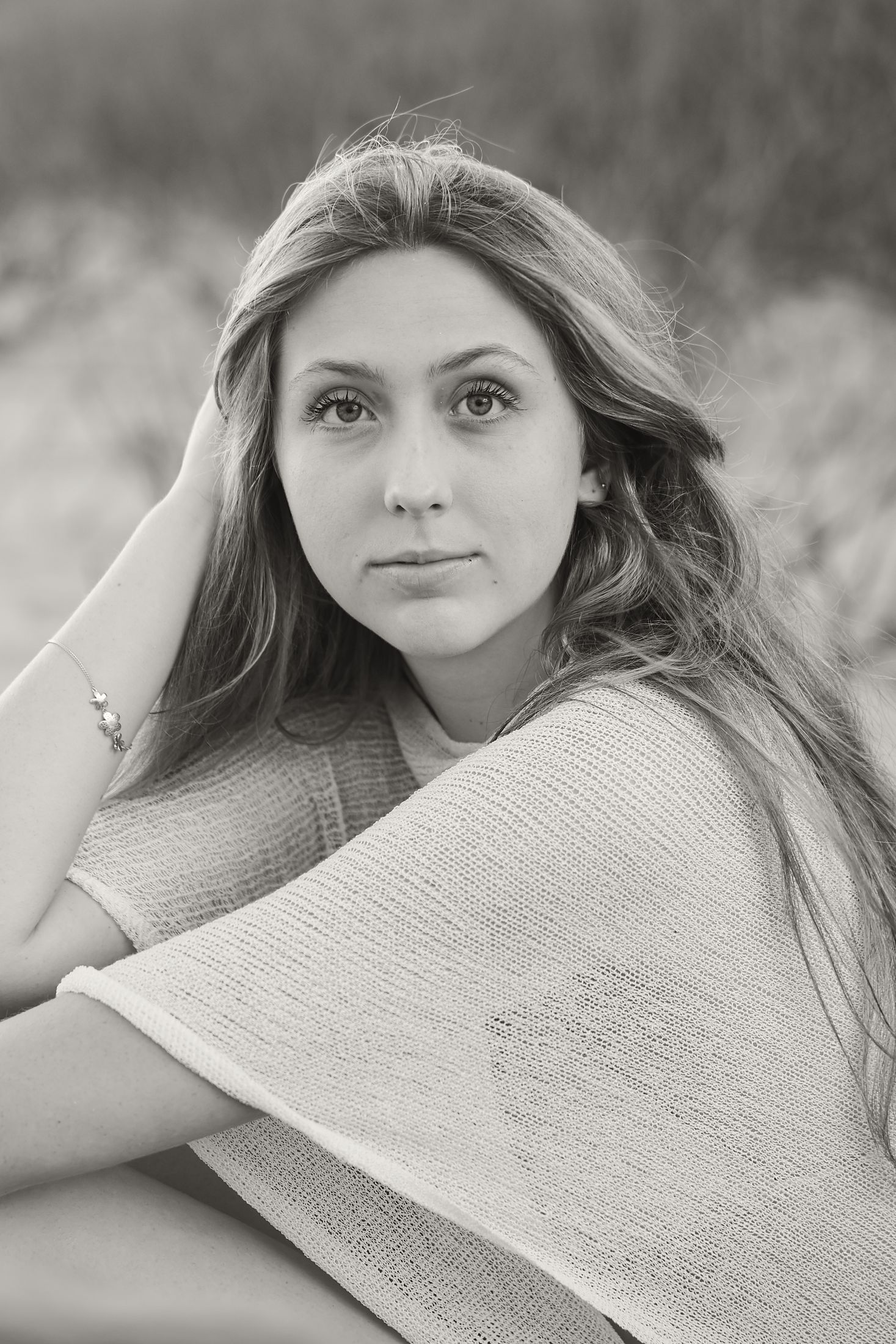 Black and white portrait of Noemi seated, chin resting near her shoulder, looking directly at the camera