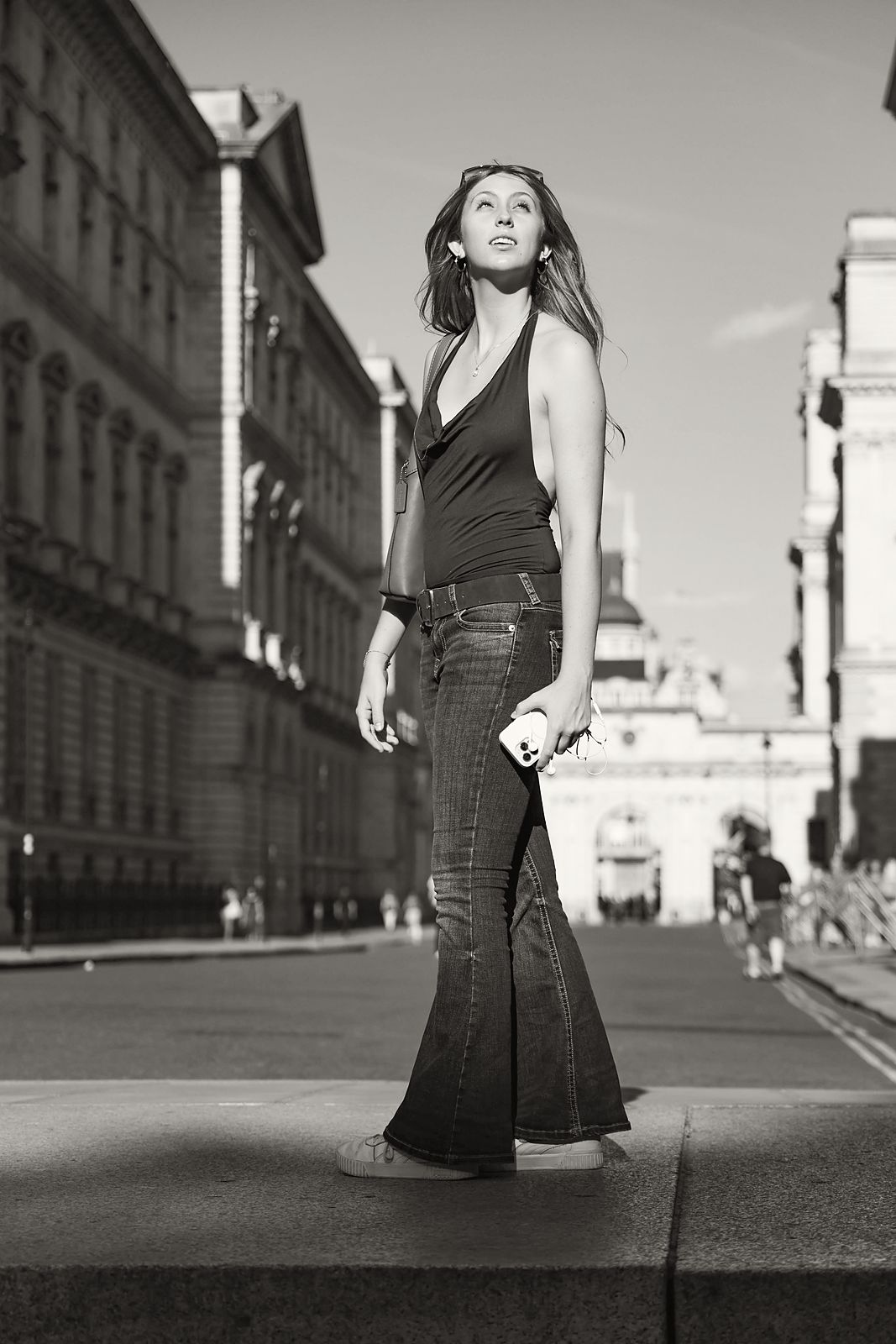 Full-length in flared jeans on a London street, looking up