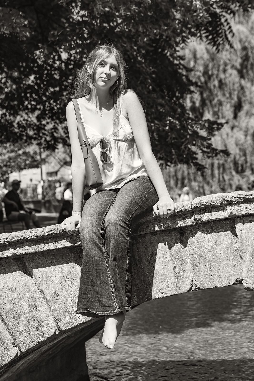 Sitting on a stone bridge wall over a stream