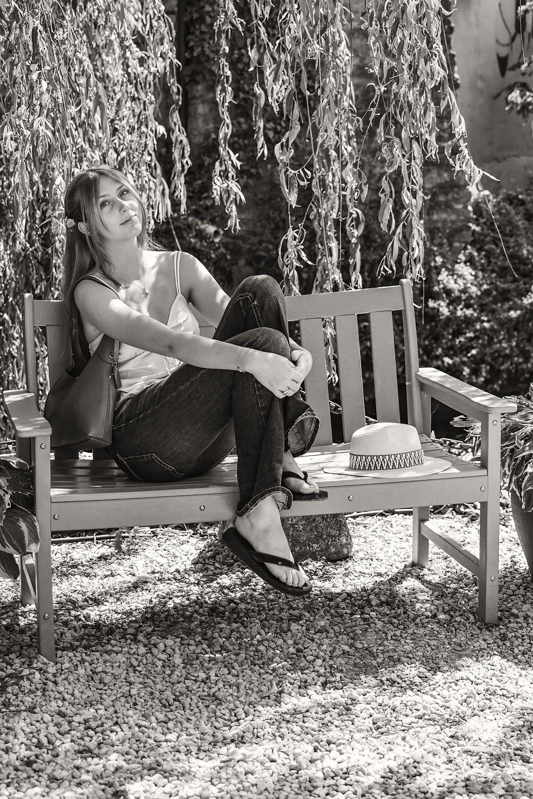 Seated on a garden bench beneath a willow, looking up