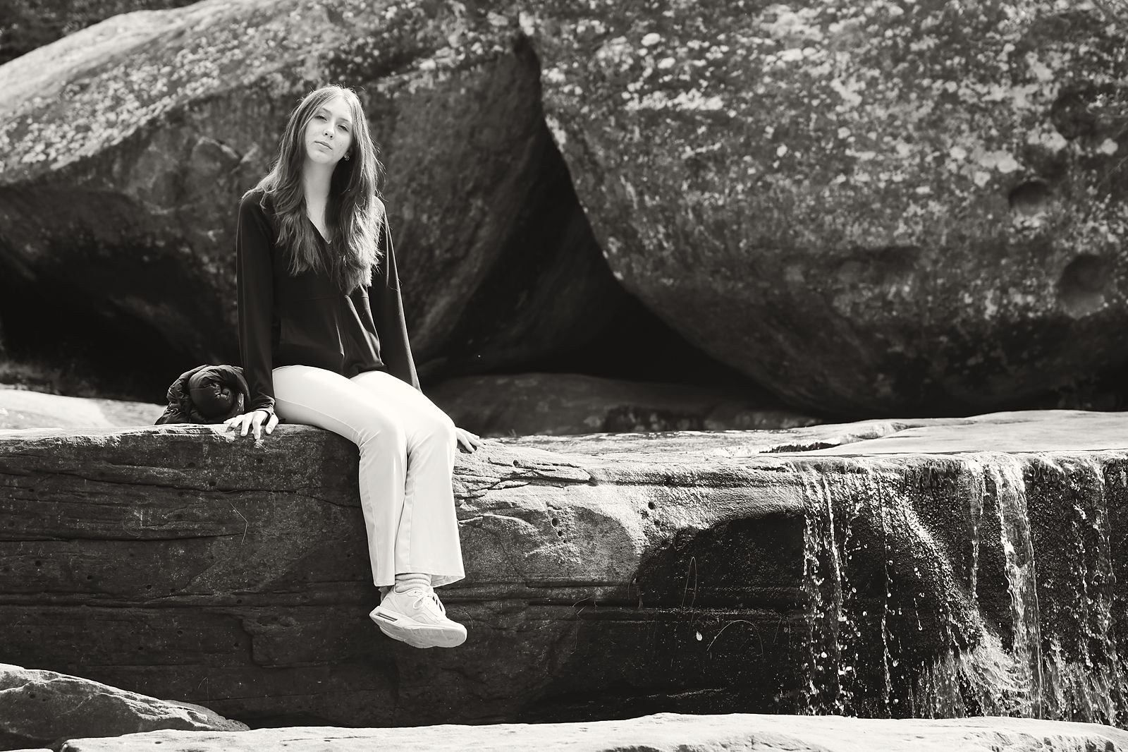 Seated on rocks beside a small waterfall